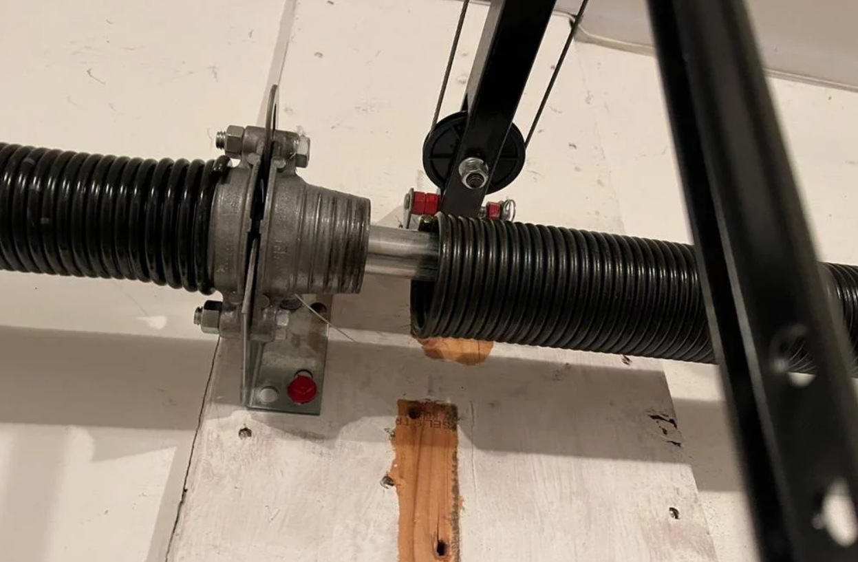 Close-up image of a professional technician fixing a garage door spring in Jupiter, FL, showcasing the detailed repair work involved in maintaining secure and functional garage doors.