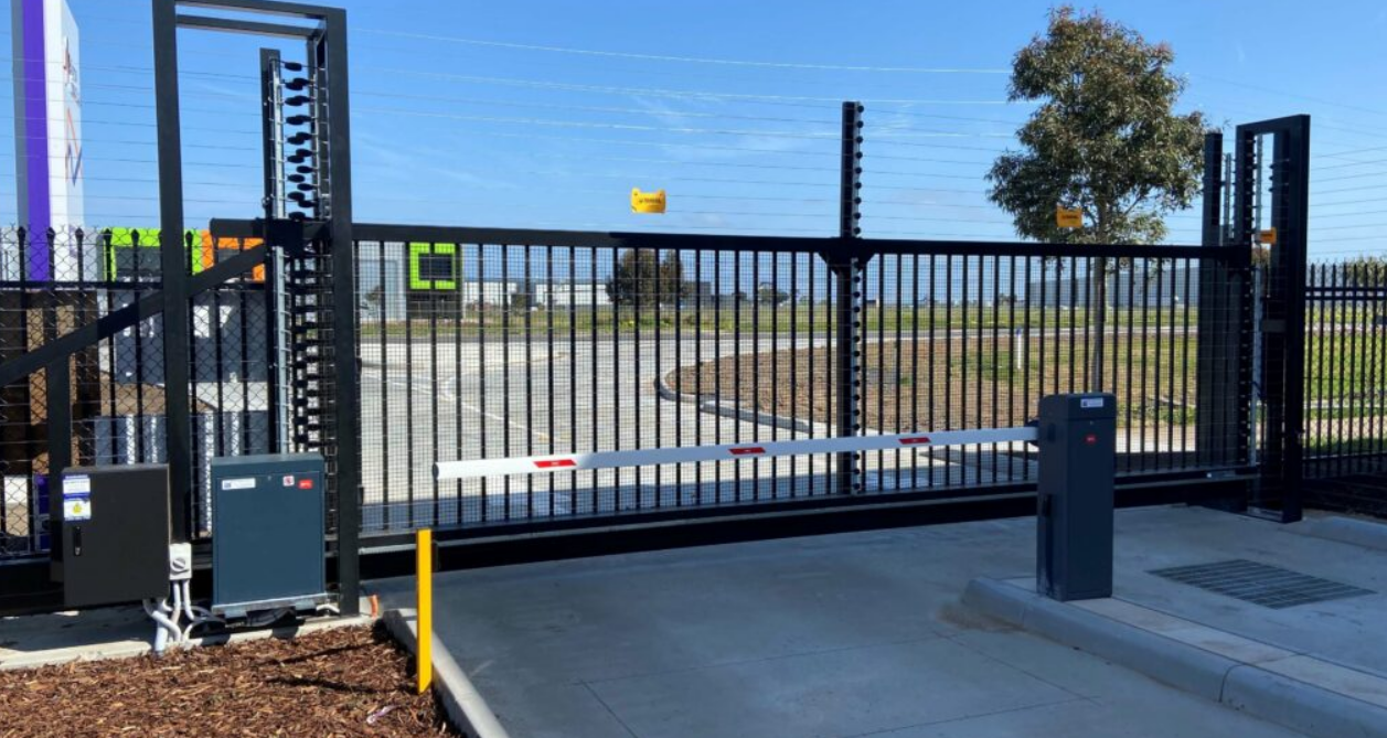 An experienced technician performing commercial gate repair in Jupiter, FL, showcasing the intricate components of a high-security automatic gate system.